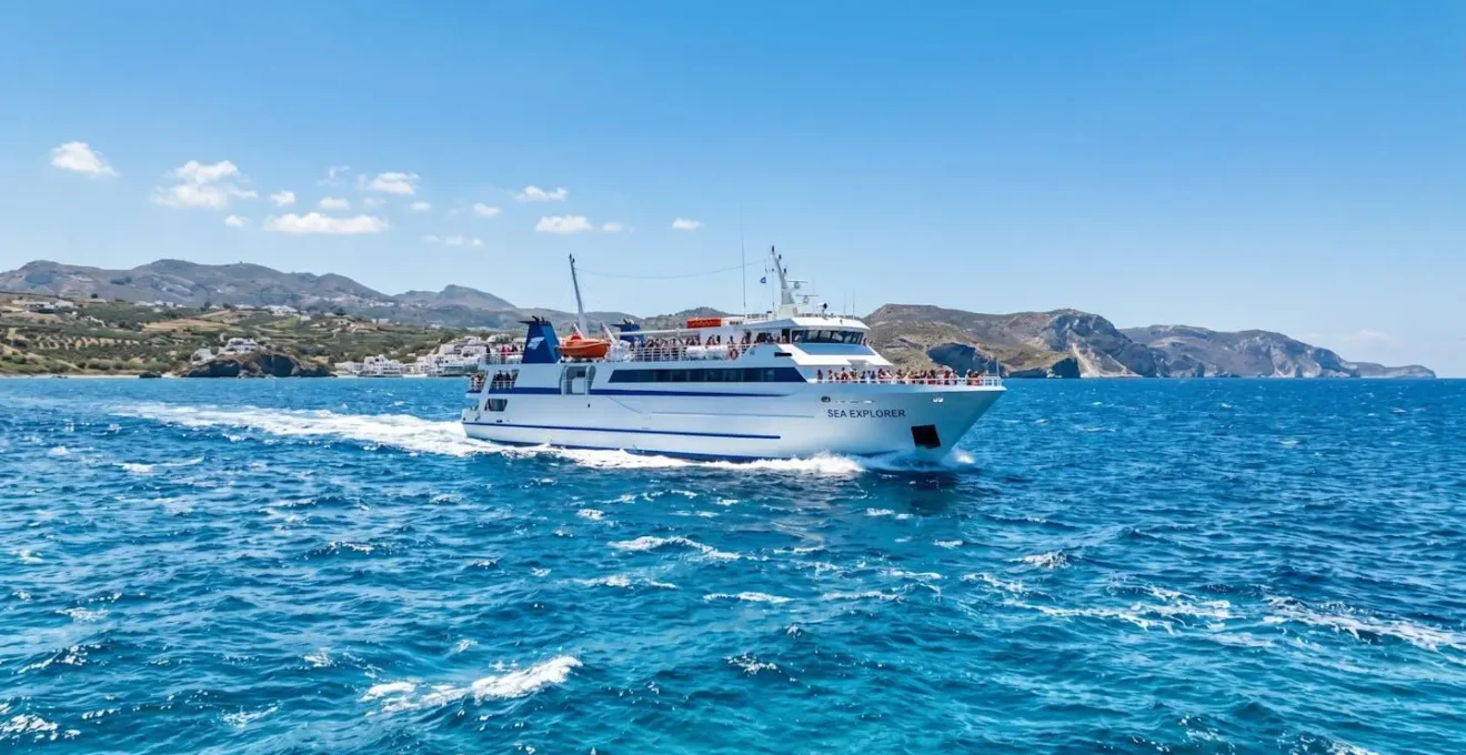 Un ferry moderne naviguant sur la mer Méditerranée sous un ciel bleu éclatant, vu depuis le pont supérieur avec une ambiance estivale lumineuse