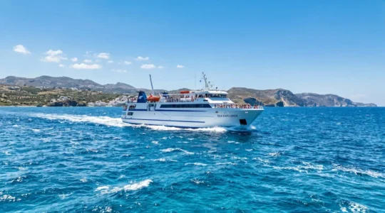 Un ferry moderne naviguant sur la mer Méditerranée sous un ciel bleu éclatant, vu depuis le pont supérieur avec une ambiance estivale lumineuse