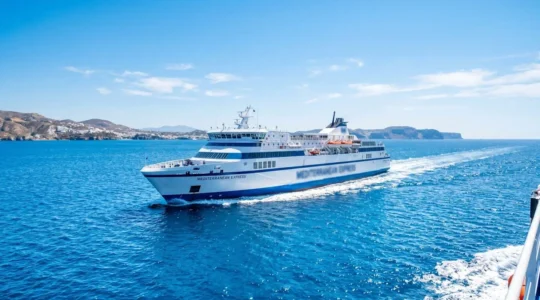 Un ferry moderne naviguant sur la mer Méditerranée sous un ciel bleu éclatant, vu depuis le pont supérieur avec une ambiance estivale lumineuse
